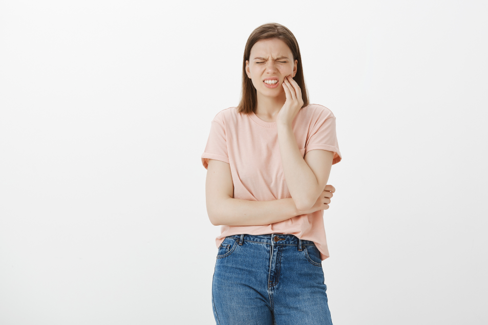 Bothered woman grimacing from pain by touching cheek
